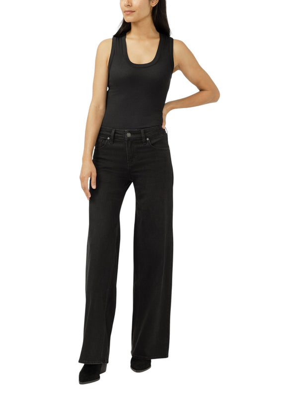 Model wearing Maison Taïga Silver Jeans Co. Suki wide leg black denim jeans with a mid-rise fit and five-pocket style.