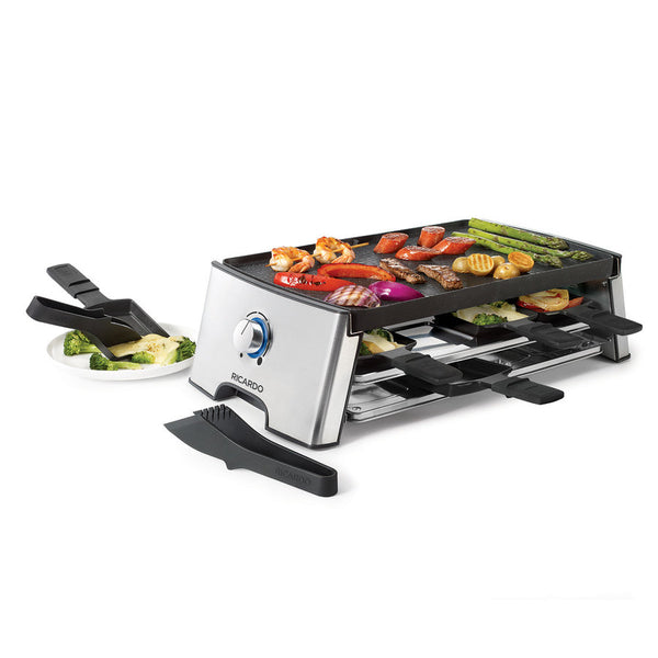 Ensemble à raclette en mode cuisson incluant pinces et cassolettes. Viandes, crevettes, saucisses, légumes, fromage en cours de cuisson